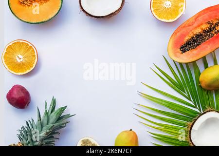 Rahmen mit tropischen Früchten und Palmenblatt auf weißem Hintergrund, Draufsicht Stockfoto