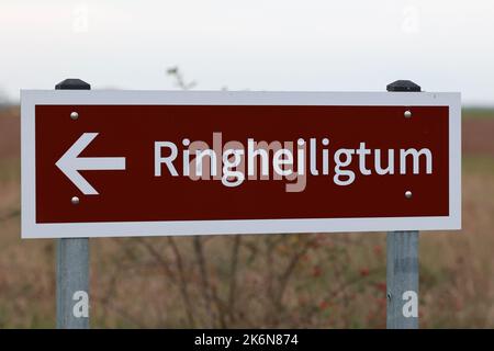 13. Oktober 2022, Sachsen-Anhalt, Pömmelte: Ein Wegweiser zeigt den Weg zum Ringheiligtum. Das rekonstruierte Ringheiligtum steht an der ursprünglichen Stelle. Das Ringheiligtum hat einen Durchmesser von 115 Metern und ist von einem Palisadenzaun aus 1800 Robinienstämmen umgeben. Pömmelte ist vergleichbar mit dem englischen Stonehenge - nur der Standort wurde aus Holz gebaut. Eine neun Meter hohe Aussichtsplattform bietet einen umfassenden Überblick. Das rund 4300 Jahre alte Ringheiligtum in Pömmelte-Zackmünde (Salzlandkreis) ist ein Touristenmagnet. Foto: Peter Gercke/dpa Stockfoto