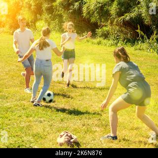 Jugendliche spielen im Sommer auf grünem Gras Fußball Stockfoto