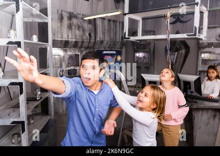Kleines Mädchen brüllt Jungen an, der im Bunker des Quest-Zimmers nach etwas greift Stockfoto