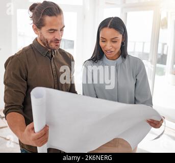 Diese Pläne sehen toll aus. Zwei junge Architekten, die sich die Baupläne vor Ort anschauen. Stockfoto