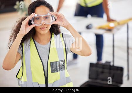 Sicherheit geht vor. Ein attraktiver junger Unternehmer, der drinnen steht und Schutzbrillen aufsetzt. Stockfoto