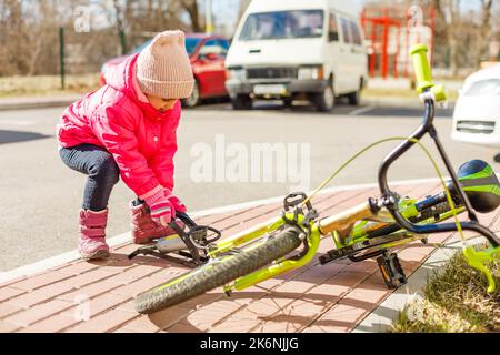 Ein kleines Mädchen pumpt einen Fahrradreifen hoch Stockfoto