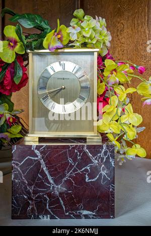 Künstliche Blumen zieren eine Howard Miller Exton Uhr, die in einem Schaufenster in Baker City, Oregon, USA, ausgestellt wird Stockfoto