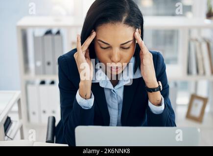 Atmen Sie tief durch und konzentrieren Sie sich. Eine junge Geschäftsfrau, die gestresst aussieht, während sie in einem Büro an einem Laptop arbeitet. Stockfoto
