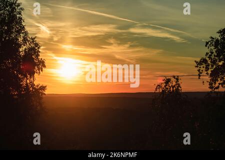 Ein wunderschöner Sonnenuntergang über einem bewaldeten Gebiet im Sommer, der eine Atmosphäre der Ruhe und Entspannung schafft Stockfoto