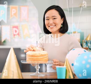 Geburtstage sind von Natur aus eine Art, uns zu sagen, mehr Kuchen zu essen. Eine junge Frau, die zu Hause Geburtstag feiert. Stockfoto