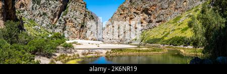 Rückblick auf den Kiesstrand Cala de Sa Calobra mit einem Teich vorne im tiefsten Canyon von Mallorca mit Blick auf die Flussmündung des Torrent de Pareis. Stockfoto