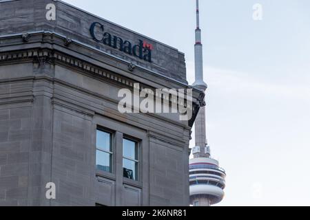 Das Logo der kanadischen Regierung ist oben auf dem Dominion Public Building in der Innenstadt von Toronto zu sehen, mit dem CN Tower im Hintergrund. Stockfoto