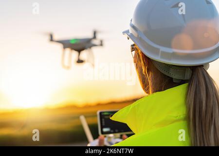 Drohneninspektion. Weibliche Betreiberin inspiziert Windturbine mit Drohne. Konzept der erneuerbaren Energien Stockfoto