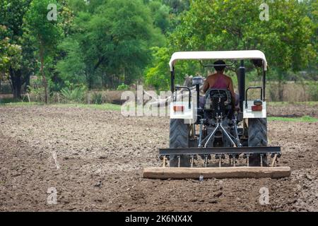 TIKAMGARH, MADHYA PRADESH, INDIEN - 04. JULI 2022: Landwirt im Traktor, der Land für die Aussaat vorbereitet. Stockfoto