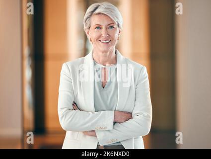 Ich besetze dieses Gebäude. Eine reife Geschäftsfrau, die bei der Arbeit mit gekreuzten Armen steht. Stockfoto