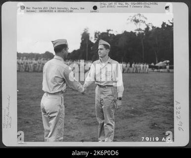 Brig. General Paul B. Wurtsmith, Commander 5. Fighter Command, gratuliert LT. WM. C. Day, Jr., Red Lion, Penn., der 49. Fighter Group, nachdem er ihm bei einer Zeremonie auf dem Flugplatz Dobodura (Horando) das Distinguished Flying Cross überreicht hatte Stockfoto