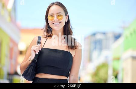 Portrait, asiatische Frau und Sonnenbrille mit Lächeln, fröhlichen und lässigen Look in der Stadt, die kantig, trendige Mode und mit Handtasche. Junges Mädchen, entspannen und Stockfoto