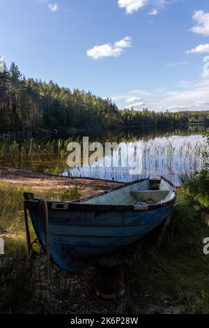 Altes blaues Fiberglas-Boot am Sandstrand im Repovesi-Nationalpark, Finnland Stockfoto