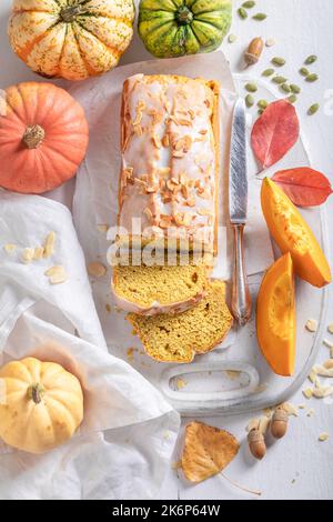 Süßer Kürbiskuchen mit Mandeln und weißer Glasur. Herbstkürbisbrot in Scheiben geschnitten. Stockfoto