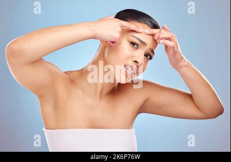 Ist dies der beste Weg, um es loszuwerden. Studioporträt einer attraktiven jungen Frau, die vor blauem Hintergrund eine Zitze auf ihr Gesicht drückt. Stockfoto