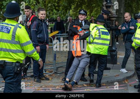 London, Großbritannien. 14.. Oktober 2022. Metropolitan Police Officers verhaften einen Klimaaktivisten von Just Stop Oil, der die Straße vor New Scotland Yard blockiert hatte, um die britische Regierung aufzufordern, die Erteilung von Öl- und Gaslizenzen einzustellen. Ein Aktivist besprühte auch das rotierende Schild von New Scotland Yard vor dem Gebäude mit gelber Farbe. Die Metropolitan Police nahm 24 Verhaftungen wegen des Verdachts der vorsätzlichen Behinderung der Autobahn und/oder der Verschwörung zur Begehung krimineller Schäden vor. Kredit: Mark Kerrison/Alamy Live Nachrichten Stockfoto