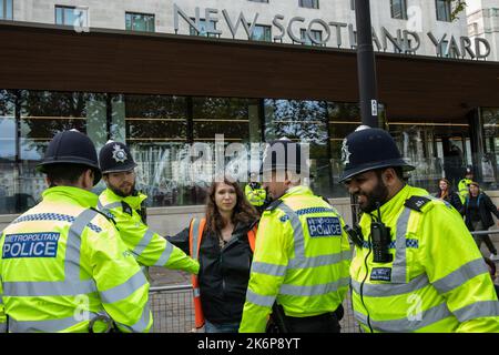 London, Großbritannien. 14.. Oktober 2022. Metropolitan Police Officers verhaften einen Klimaaktivisten von Just Stop Oil, der die Straße vor New Scotland Yard blockiert hatte, um die britische Regierung aufzufordern, die Erteilung von Öl- und Gaslizenzen einzustellen. Ein Aktivist besprühte auch das rotierende Schild von New Scotland Yard vor dem Gebäude mit gelber Farbe. Die Metropolitan Police nahm 24 Verhaftungen wegen des Verdachts der vorsätzlichen Behinderung der Autobahn und/oder der Verschwörung zur Begehung krimineller Schäden vor. Kredit: Mark Kerrison/Alamy Live Nachrichten Stockfoto