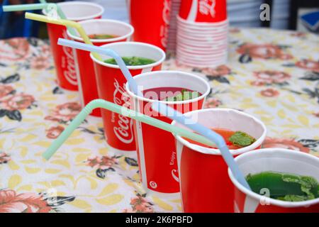 Kräutersaft, der in einer Coca-Cola-Tasse gegossen und an einem heißen, sonnigen Tag auf einem Tisch ausgestellt wurde Stockfoto