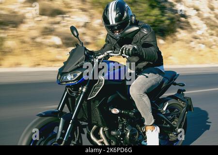 Nahaufnahme eines Motorradfahrers, der mit Bewegungsunschärfen auf der Autobahn unterwegs ist. Stockfoto