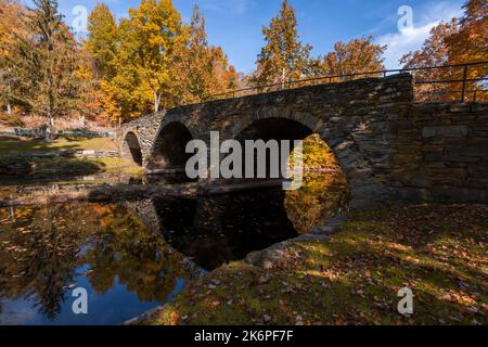 Stone Arch Bridge in Callicoon, NY, Catskill Mountains, umgeben von brillantem Herbstlaub an einem hellen Herbstmorgen Stockfoto