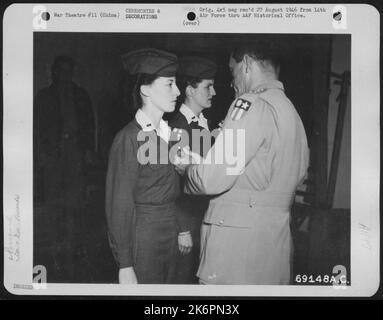 Vierzehntes Luftwaffenhauptquartier, China -- 'für verdienstvolle Erfolge im Luftflug' 1. LT. Madeline M. Norris, links, aus Hollis, New York, Army Nurse, die einem medizinischen Luftevakuierungsgeschwader in Einem Flügel der 14. Luftstreitkräfte zugewiesen wurden, empfängt die Air Me Stockfoto