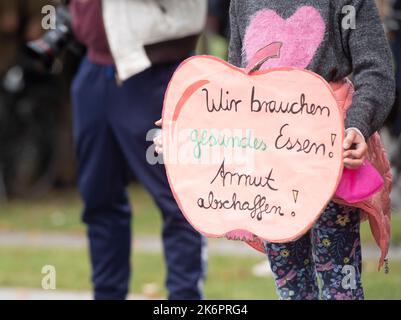 Berlin, Deutschland. 15. Oktober 2022. Ein Kind hält ein Poster mit der Aufschrift „Wir brauchen gesunde Nahrung!“ Bei der Kundgebung der Initiative #ichbinarmutsverraten im Bundeskanzleramt. Armut abschaffen!“. #IchBinArmutsverraten ist ein Hashtag, der seit Mai 2022 im sozialen Netzwerk Twitter verbreitet wird. Von Armut betroffene Menschen berichten über ihre Erfahrungen und Probleme. Quelle: Paul Zinken/dpa/Alamy Live News Stockfoto