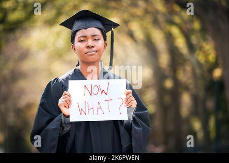 Was mache ich jetzt mit meinem Leben? Porträt einer jungen Frau mit einem Schild, das jetzt liest, was am Abschlusstag. Stockfoto
