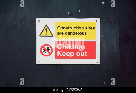 Kinder halten am Sicherheitsschild auf der Baustelle ein Schild aus Stockfoto