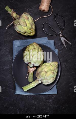 Ungekochte violette Artischocken auf schwarzem Hintergrund Stockfoto