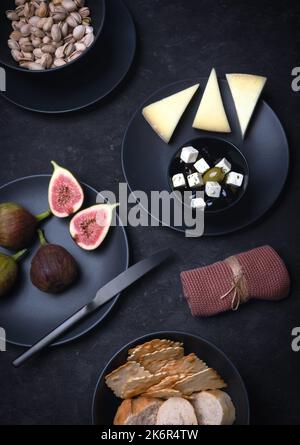 Käseplatte mit Käse und Nüssen, mediterrane Speisen auf schwarzem Hintergrund Stockfoto