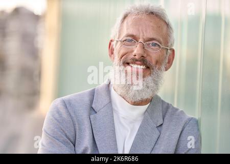 Lächelnder, glücklicher älterer Geschäftsmann, der im Freien steht, ein Kopfbildnis. Stockfoto