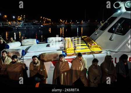 Roccella Jonica, Italien. 14. Oktober 2022. Migranten sahen, wie sie sich auf dem Patrouillenboot mit Decken bedeckten. Patrouillenboote der italienischen Küstenwache befahren zwei verschiedene Gruppen von Migranten (99 Personen in der ersten, 83 in der zweiten, beide von der türkischen Route) im Hafen „Porto delle Grazie“ von Roccella Jonica. Die große Mehrheit der Migranten stammt aus dem Iran, dem Irak, Afghanistan und Syrien, bei der zweiten Ankunft kommen Menschen aus Bangladesch. Ärzte ohne Grenzen und das lokale Komitee des Roten Kreuzes unterstützten Migranten im Hafen. Kredit: SOPA Images Limited/Alamy Live Nachrichten Stockfoto