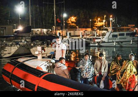 Roccella Jonica, Italien. 14. Oktober 2022. Migranten mit Wärmedecken auf einem Patrouillenboot gesehen. Patrouillenboote der italienischen Küstenwache befahren zwei verschiedene Gruppen von Migranten (99 Personen in der ersten, 83 in der zweiten, beide von der türkischen Route) im Hafen „Porto delle Grazie“ von Roccella Jonica. Die große Mehrheit der Migranten stammt aus dem Iran, dem Irak, Afghanistan und Syrien, bei der zweiten Ankunft kommen Menschen aus Bangladesch. Ärzte ohne Grenzen und das lokale Komitee des Roten Kreuzes unterstützten Migranten im Hafen. Kredit: SOPA Images Limited/Alamy Live Nachrichten Stockfoto