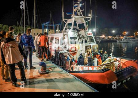 Roccella Jonica, Italien. 14. Oktober 2022. Mitglieder der Küstenwache während der Ausschiffung gesehen. Patrouillenboote der italienischen Küstenwache befahren zwei verschiedene Gruppen von Migranten (99 Personen in der ersten, 83 in der zweiten, beide von der türkischen Route) im Hafen „Porto delle Grazie“ von Roccella Jonica. Die große Mehrheit der Migranten stammt aus dem Iran, dem Irak, Afghanistan und Syrien, bei der zweiten Ankunft kommen Menschen aus Bangladesch. Ärzte ohne Grenzen und das lokale Komitee des Roten Kreuzes unterstützten Migranten im Hafen. Kredit: SOPA Images Limited/Alamy Live Nachrichten Stockfoto
