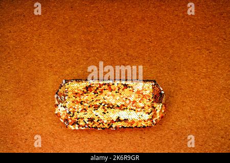 Damen-Kosmetiktasche aus goldenem Glitter auf Korkhintergrund. Stockfoto