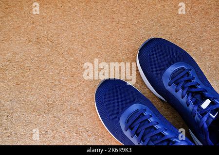 Flach Legen Sie ein Paar blaue Sportschuhe auf einem braunen Korkgrund. Konzept gesunder Lebensstil und Sport. Stockfoto