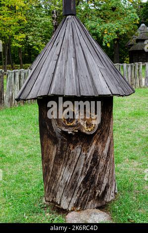 Rustikale Holzhütte in einem Wald aus dem Stamm eines Baumes mit einem geschnitzten Schindeldach gebildet stehen in einem grünen Wald froh Stockfoto