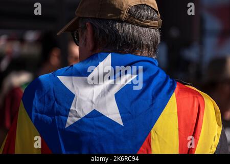 Barcelona, Spanien. 15. Oktober 2022. Ein Aktivist für die Unabhängigkeit Kataloniens wird mit einer Flagge umhüllt abgebildet die separatistische Zivileinheit Assemble Nacional Catala (ANC) beginnt ihre politische Kampagne "Wir beschuldigen die spanische Justiz" mit einem zweitägigen Nachtlager auf der Plaza de Catalunya, um den politischen Prozess der Unabhängigkeit Kataloniens zu fördern. (Foto von Paco Freire/SOPA Images/Sipa USA) Quelle: SIPA USA/Alamy Live News Stockfoto