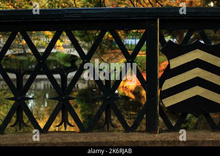 Gold nach oben Chevrons auf einem schwarzen Schild auf einer Brücke in Roath Park, Cardiff, Wales Stockfoto