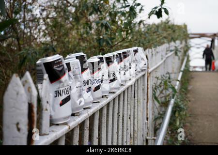 Reihe von umgedrehten leeren Carling-Bierdosen auf Geländer auf einer Brücke. Stockfoto