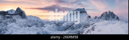 Panorama atemberaubender Blick auf den Sonnenaufgang über der verschneiten Bergkette mit buntem Himmel im Winter auf dem Segla Mount auf der Insel Senja, Norwegen Stockfoto