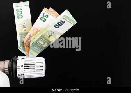 Heizthermostat, ausgestattet mit Euro-Banknoten, schwarzer Hintergrund Stockfoto