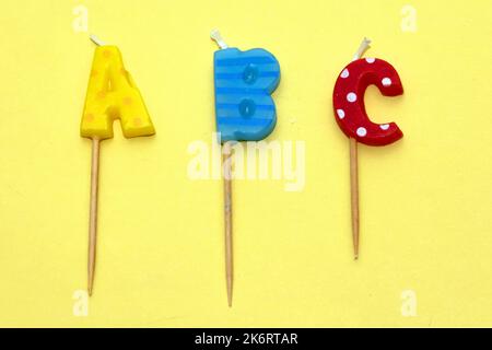 ABC Alphabet bunte Kerzen Text Buchstaben isoliert auf gelbem Hintergrund Stockfoto