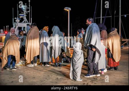 Roccella Jonica, Italien. 14. Oktober 2022. Migranten sahen, wie sie sich bei ihrer Ankunft im Hafen mit Decken bedeckten. 64 irreguläre Migranten, hauptsächlich aus Afghanistan, dem Iran, Syrien und dem Irak, wurden von der italienischen Küstenwache unterstützt und landeten in „Porto delle Grazie“, dem Hafen von Roccella Ionica, der aus der Türkei kam. Die Menschen wurden von Doctors Without Borders und dem lokalen Komitee des Roten Kreuzes unterstützt.Quelle: SOPA Images Limited/Alamy Live News Stockfoto