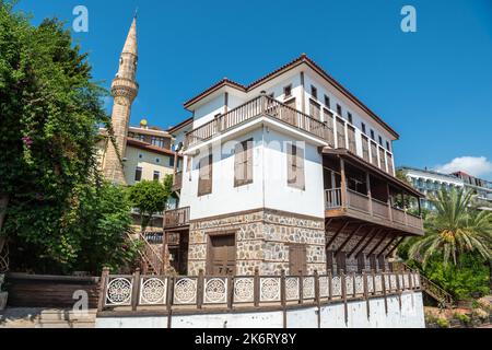 Alanya, Türkei – 18. August 2021. Historisches osmanisches Herrenhaus in der Rihtim Caddesi Straße in Alanya, mit Minarett der Haci Kadiroglu Camii Moschee im Hintergrund Stockfoto