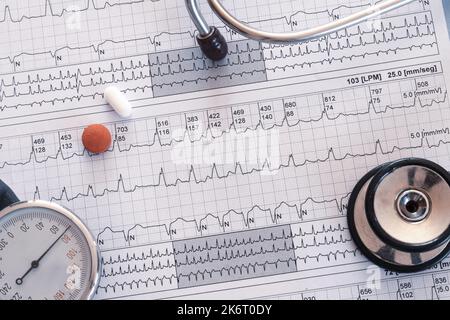 Elektrokardiogramm mit supraventrikulärer Tachykardie und farbigen Pillen. Medizinisches Schreibtischkonzept oder flache Verlegung. Stockfoto