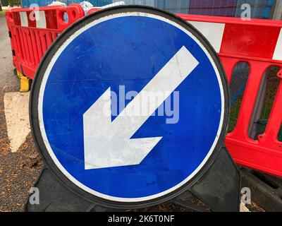 Nahaufnahme des blauen runden Verkehrszeichens mit einem weißen Pfeil nach links, der auf Keep Left zeigt. Stockfoto
