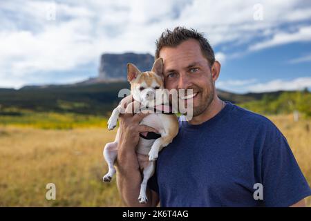 Mann mit seinem besten Freund und Reisegefährten mit dem Chefberg im Hintergrund, dem Glacier National Park. Stockfoto